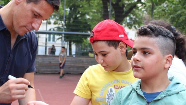 Ein Mann gibt zwei Jungen ein Autogramm.