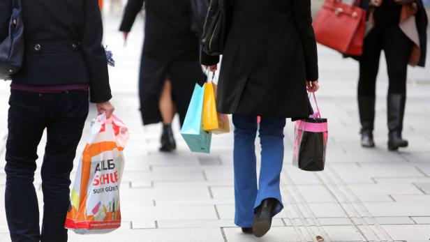 Mehrere Personen sind mit Einkaufstüten in der Stadt unterwegs.