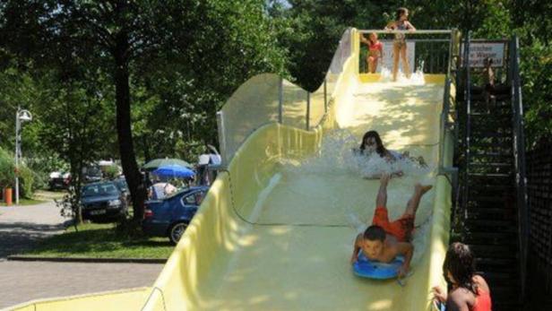 Kinder rutschen eine gelbe Wasserrutsche hinunter.