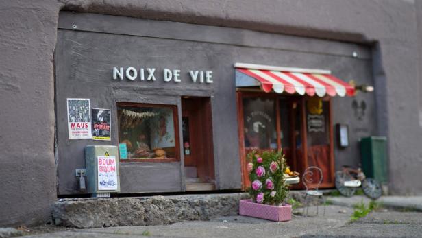 Eine Miniaturansicht eines Ladens mit der Aufschrift „Noix de Vie“ und kleinen Details wie Plakaten und Blumen.