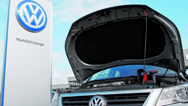 Ein Volkswagen Nutzfahrzeug mit geöffneter Motorhaube vor einem VW-Schild.