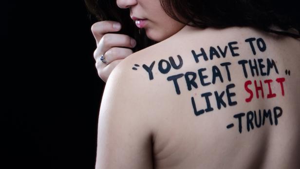 Auf dem Rücken einer Frau steht ein Zitat von Trump: „You have to treat them like shit.“.
