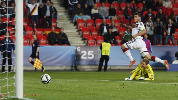 Ein deutscher Fußballspieler springt über den Torwart während eines Spiels.