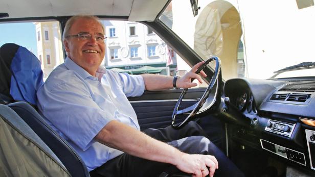 Ein lächelnder Mann sitzt am Steuer eines Oldtimers.