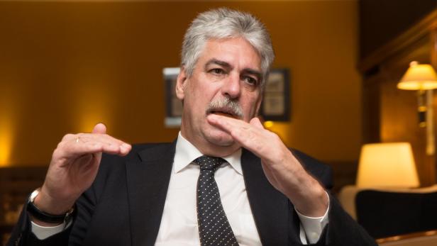 Ein Mann mit grauem Haar und Schnurrbart gestikuliert mit den Händen.