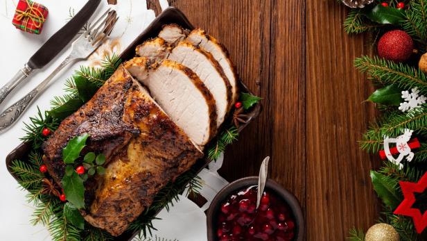 Ein festlicher Braten mit Preiselbeersauce und weihnachtlicher Dekoration.