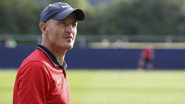 Ein Mann mit Kappe und rotem Hemd blickt nachdenklich zur Seite.