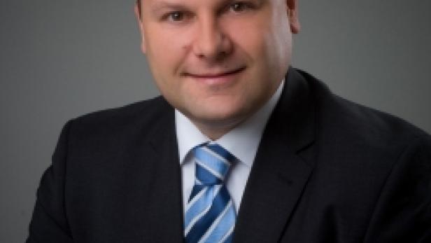 Ein Mann mit Anzug und Krawatte lächelt in die Kamera.