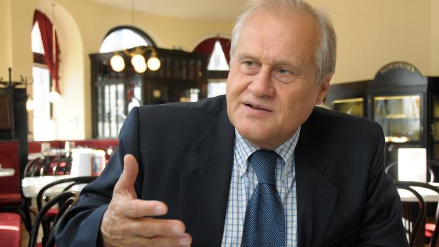 Ein Mann im Anzug gestikuliert in einem Café.