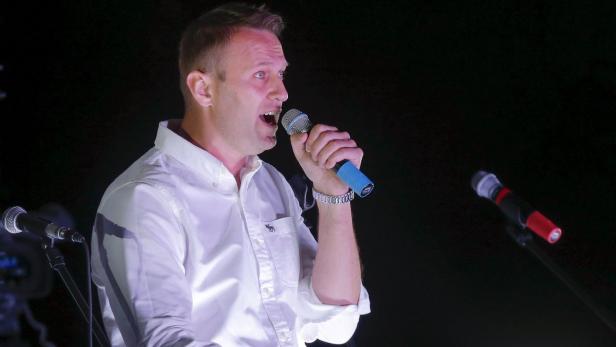 Ein Mann mit weißem Hemd spricht in ein Mikrofon.