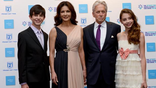 Michael Douglas, Catherine Zeta-Jones und ihre Kinder posieren vor einer Wand mit dem Logo des Genesis-Preises.