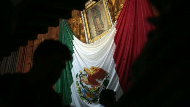 Eine mexikanische Flagge hängt vor einem Gemälde der Jungfrau von Guadalupe.