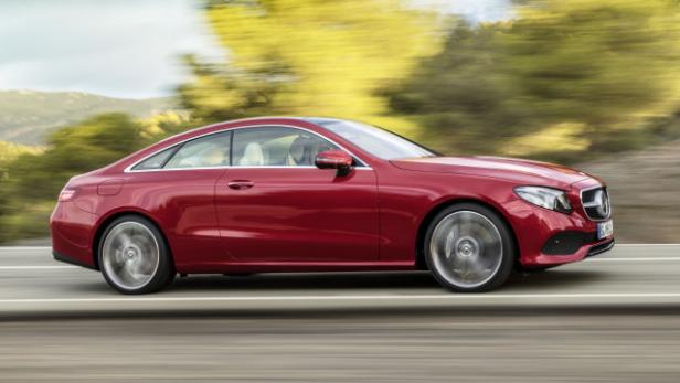 Ein rotes Mercedes-Benz E-Klasse Coupé fährt auf einer Landstraße.