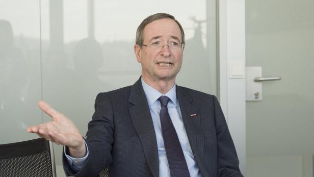 Ein Mann mit Brille und Anzug gestikuliert in einem Gespräch.