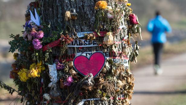 Ein Baumstamm ist mit Blumen, einem Papierkranich und einem roten Herz geschmückt.