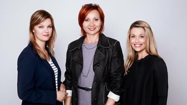 Drei Frauen posieren vor einem hellen Hintergrund.