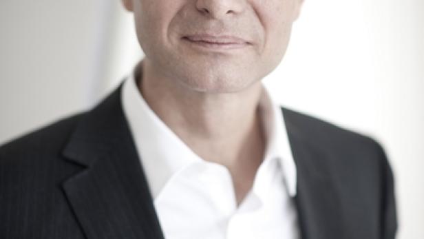 Ein Mann mit Brille und Anzug blickt in die Kamera.