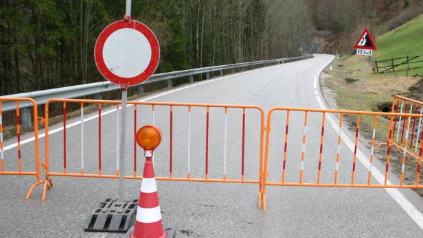Eine gesperrte Straße mit einem Warnschild vor Steinschlag in 12,5 km Entfernung.