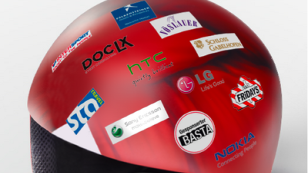 Ein roter Helm mit verschiedenen Aufklebern von Marken wie HTC, Nokia und LG.
