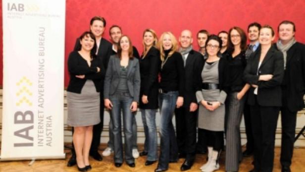Eine Gruppe von Personen posiert vor einem Banner des IAB Austria.