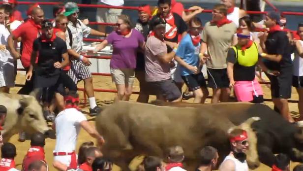 Beim Stiertreiben in Pamplona rennen Menschen vor den Stieren weg.