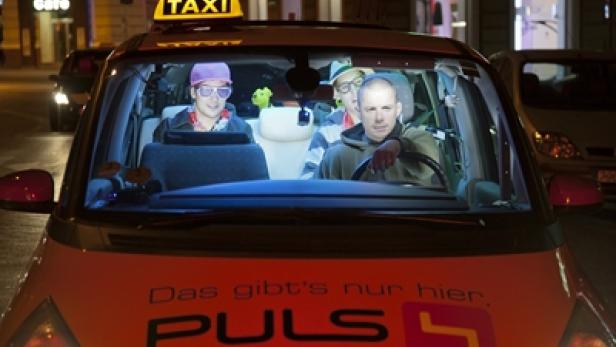 Ein Taxi mit vier Personen, die Hüte und bunte Accessoires tragen.