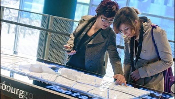 Zwei Frauen betrachten ein beleuchtetes Modell einer Stadt.
