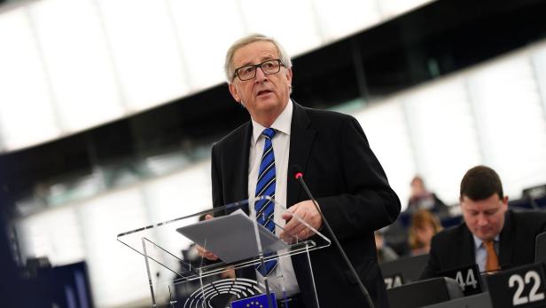 Jean-Claude Juncker in Anzug ung Krawatte hinter einem Mikrofon und einem Pult