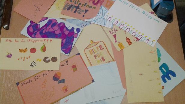 Handgezeichnete Karten mit der Aufschrift „Hilfe für die Philippinen“ liegen auf einem Tisch.