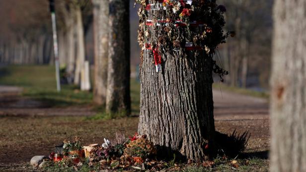 Ein Baum am Straßenrand ist mit Blumen und Bändern geschmückt.