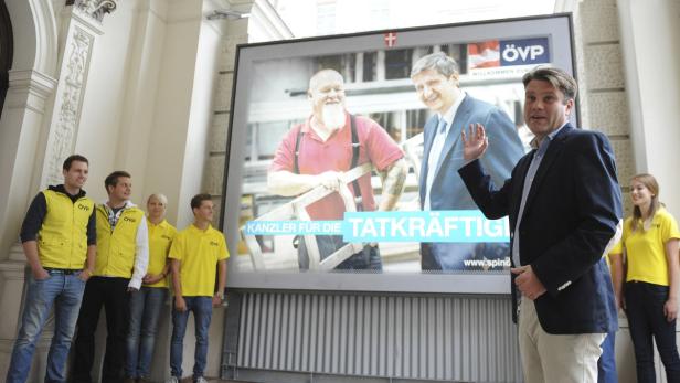 Ein Politiker der ÖVP posiert vor einem Wahlplakat mit einem Handwerker.