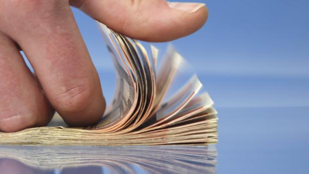 Hand counting money, closeup on blue background with reflections