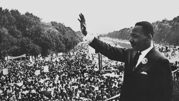 ARCHIV - Der amerikanische Führer der Schwarzen, Dr. Martin Luther King, winkt am 28.08.193 von der Lincoln Gedächtnisstätte in Washington den Demonstranten zu. Die Bürgerrechtslage für Afroamerikaner hat sich seit der berühmten Rede von Martin Luther King 1963 deutlich verbessert. Doch der Rassismus in den USA gehört längst nicht der Vergangenheit an. Foto: dpa (zu dpa-Themenpaket ««Noch nicht angekommen» - Rassismus in den USA 50 Jahre nach King» vom 27.08.2013) +++(c) dpa - Bildfunk+++