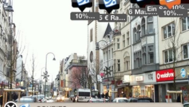 Eine belebte Einkaufsstraße mit einer Kirche im Hintergrund und Werbeanzeigen im Vordergrund.