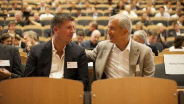 Zwei Männer unterhalten sich während einer Konferenz in einem Auditorium.