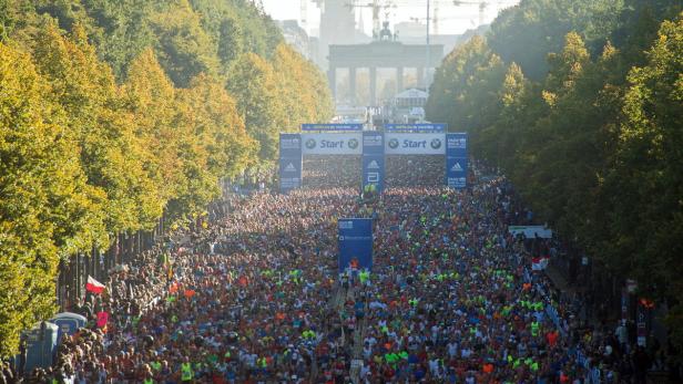 Eine große Menschenmenge läuft den Berlin-Marathon in Richtung Brandenburger Tor.