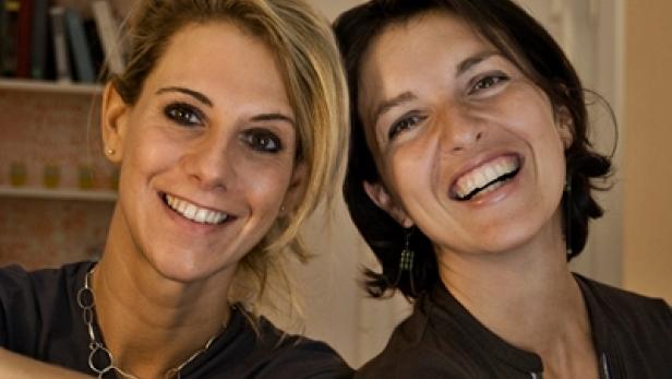 Zwei lachende Frauen posieren für ein Foto.