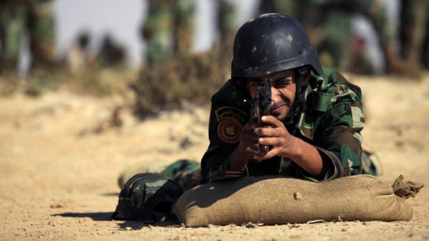 Ein Soldat in Tarnuniform zielt mit einer Pistole im Liegen.