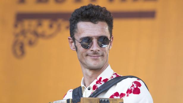 Ein Mann mit Sonnenbrille und Blumenhemd spielt Akkordeon.