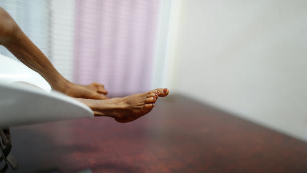 Die Füße einer Person ruhen auf einer weißen Oberfläche.