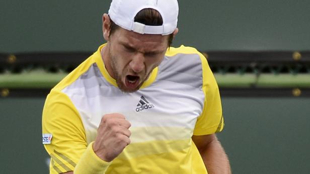 Ein Tennisspieler in gelbem Shirt und weißer Kappe ballt die Faust vor Freude.