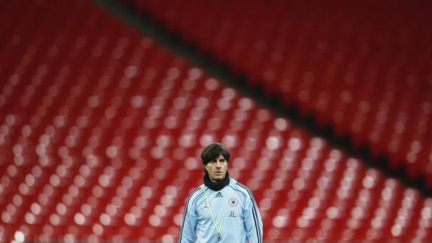 Joachim Löw steht vor leeren roten Zuschauerrängen.