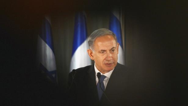 Benjamin Netanjahu spricht vor israelischen Flaggen.