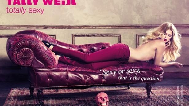 Eine Frau liegt auf einer roten Couch, mit einer pinkfarbenen Totenkopf-Dekoration im Vordergrund.