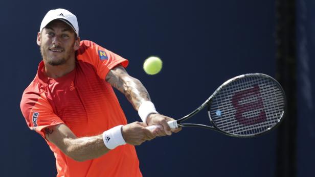 Ein Tennisspieler schlägt einen Ball mit seinem Schläger.