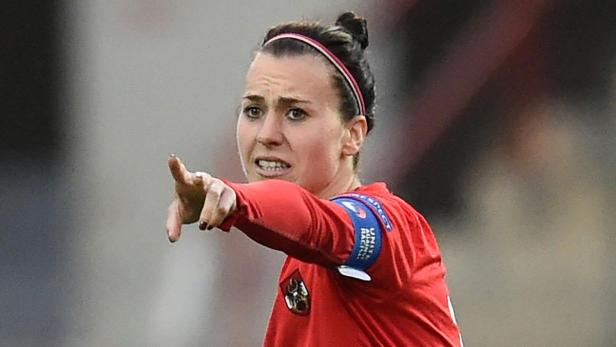Eine österreichische Fußballspielerin zeigt mit dem Finger in eine Richtung.