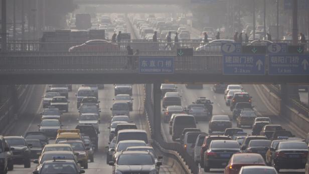 Starker Verkehr auf einer mehrspurigen Straße in Peking unter einer Fußgängerbrücke hindurch.