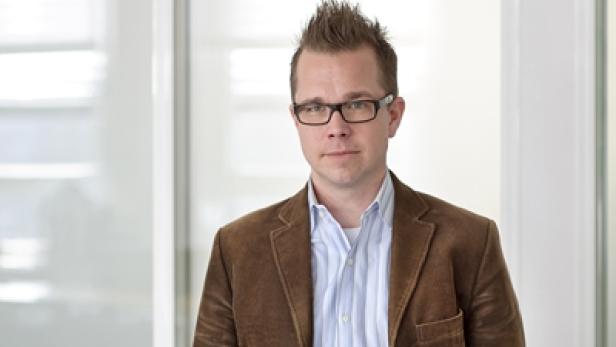 Ein Mann mit Brille und braunem Cordjackett blickt in die Kamera.