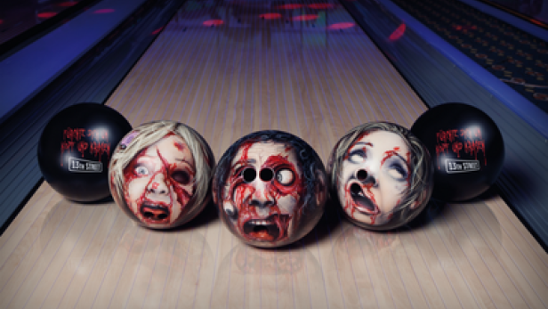 Bowlingkugeln mit Zombiegesichtern stehen auf einer Bowlingbahn.