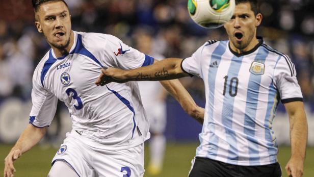 Ein Fußballspieler von Bosnien-Herzegowina im Zweikampf mit Sergio Agüero von Argentinien.